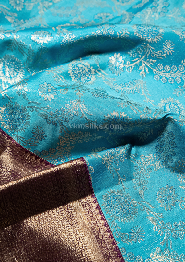 9 - 2026-09-03T174712.555 Rich Mayil blue body with intricate zari floral weaving, paired with a classic deep maroon antique gold border.